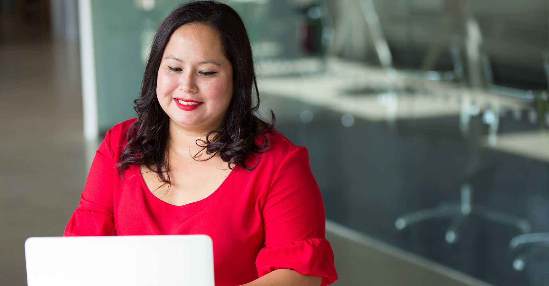 Woman in red shirt working at laptop