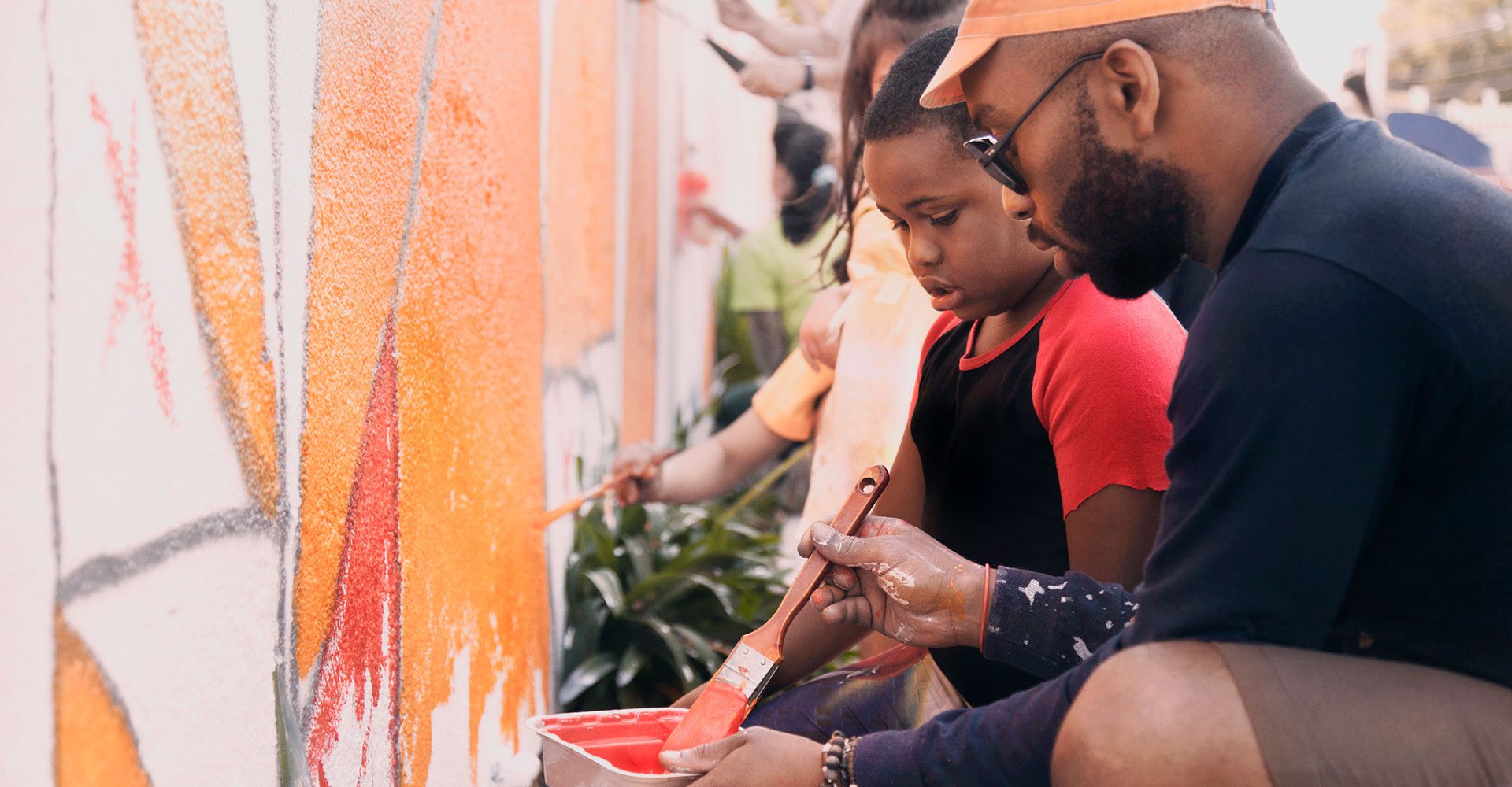 man and child painting mural on wall
